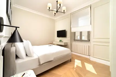 a white bedroom with a bed and a television at Vucino Suites in Istanbul
