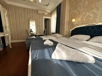 a bedroom with two beds and a woman sitting at a table at Istanbul Allyon Hotel Taxim City Center in Istanbul
