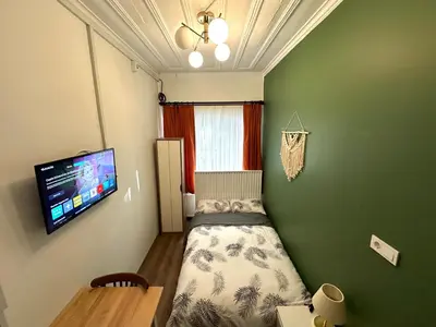 a small bedroom with a bed and a tv on the wall at Yellowhouse Room 1 in Istanbul