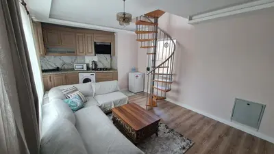 a living room with a white couch and a spiral staircase at Cozy Duplex Next to Green Masjid in Yıldırım