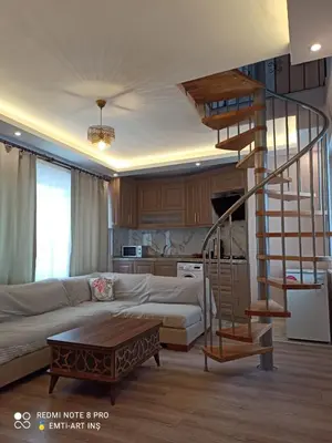a living room with a couch and a spiral staircase at Cozy Duplex Next to Green Masjid in Yıldırım