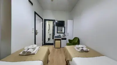 a white room with two beds and a mirror at Hotel Mara İstanbul in Istanbul
