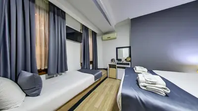 two beds in a room with blue curtains at Hotel Mara İstanbul in Istanbul