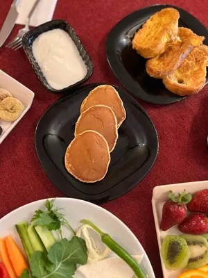 a table with two plates with pancakes and fruit and vegetables at Yakut Hotel in Istanbul