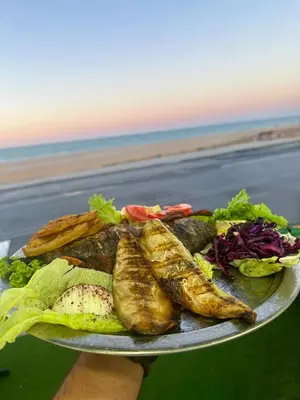 a person holding a plate of food on the beach at İstanbul Airport Black Sea Hotel in Arnavutköy