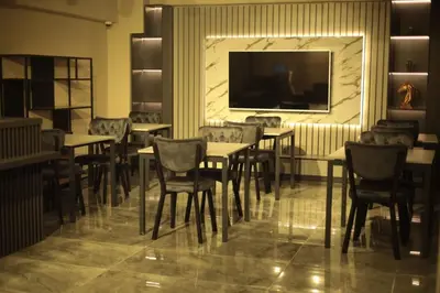 a restaurant with tables and chairs and a flat screen tv at BZN Airport Hotel in Arnavutköy