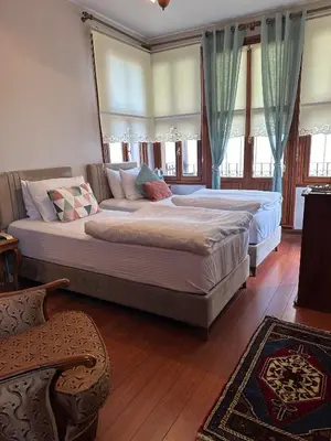 two large beds in a bedroom with wooden floors and windows at Ottoman Suites by Sera House in Istanbul