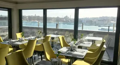 a restaurant with yellow chairs and tables and windows at Nordstern Hotel Galata in Istanbul