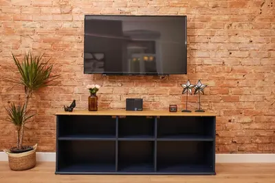 a television hanging on a brick wall with a desk at Charming 2BR AC in Center - Santur D1 in Istanbul
