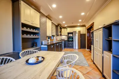 a kitchen with a wooden table and white chairs at Boğaz Manzaralı Havuzlu Lüks Villa in Istanbul
