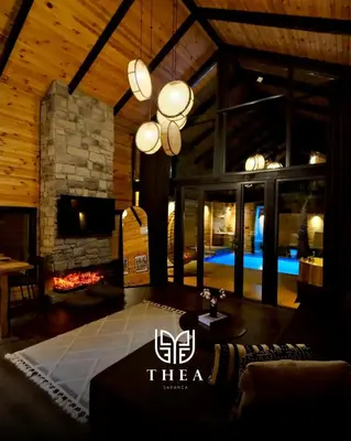 a living room with a stone fireplace and a chandelier at THEA Sapanca Bungalov in Dilekli