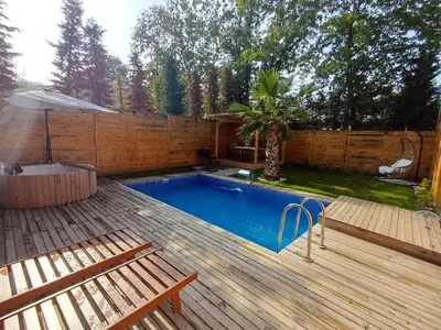 a swimming pool with two benches and a wooden deck at THEA Sapanca Bungalov in Dilekli