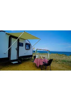 a camper on the beach with a table and chairs at HUZURLU BİR TATİl - CARAVAN SERENITY in Domalı