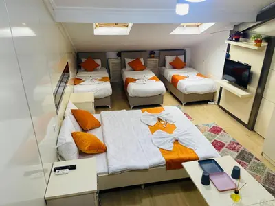 a room with four beds and a desk and a tv at Taksim Gold House Hotel in Istanbul