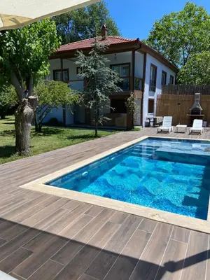 a swimming pool with a wooden deck and a house at Efe Köy Evi in Sapanca