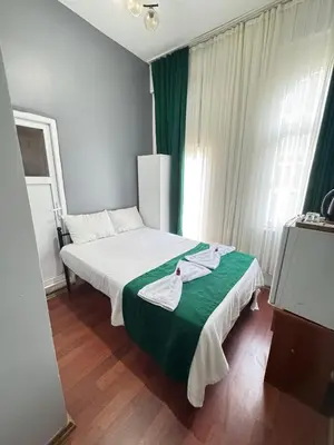 a bedroom with a bed with white sheets and green blanket at Taksim Plaza Suite in Istanbul
