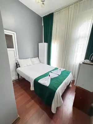 a bedroom with a bed with white sheets and green blanket at Taksim Plaza Suite in Istanbul