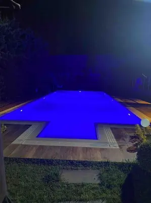 a large blue swimming pool in a dark room at Tuzlada Ferah Alani Havuz,Bahçe ve tüm rahatlıklar kişiye özel alan in Tuzla