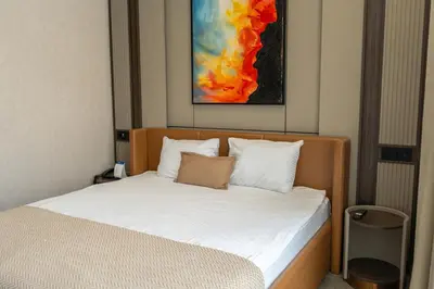 a bedroom with a bed with white sheets and a painting at Byon Hotel Şile in Sile