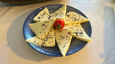 a blue plate with cheese and a tomato on it at Ottoman Hotel Sakarya in Sakarya