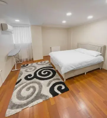 a bedroom with a bed and a rug on a wooden floor at Ground floor apartment in a quiet area 17 in Istanbul
