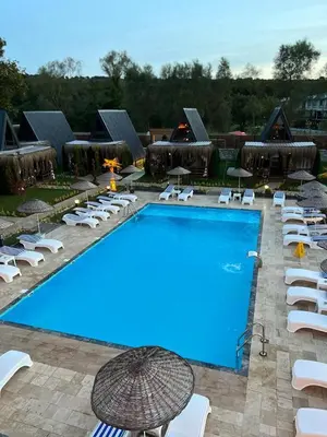 a large swimming pool with white chairs and umbrellas at Kerpe Bungalov Hotel in Kandıra