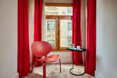 a red chair sitting in front of a window with red curtains at Stunning 2BR 1 Min Metro&Galata in Istanbul