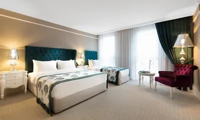 a hotel room with two beds and a red chair at Metropolitan Hotels Taksim in Istanbul