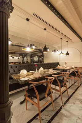 a dining room with tables and chairs and a kitchen at Metropolitan Hotels Taksim in Istanbul