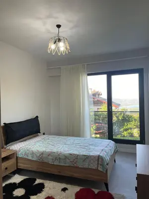 a bedroom with a bed and a chandelier and a window at Havuzlu Villa-Kartepe in Masukiye