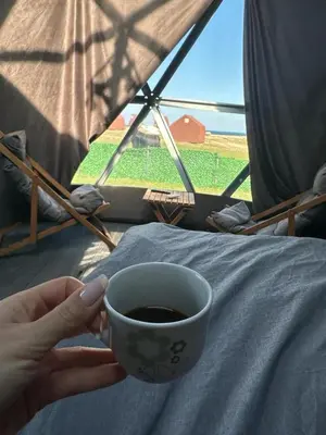 a person holding a cup of coffee in front of a tent at Kackar Kamp istanbul in Domalı