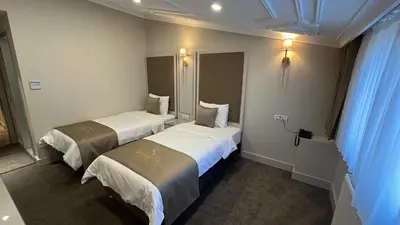 two beds in a hotel room with blue curtains at Espoir HOTEL in Istanbul