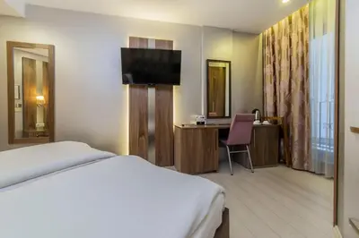 a hotel room with a bed and a desk and a television at Royal Capital Hotel Bursa in Bursa