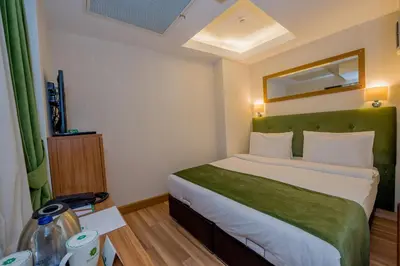 a bedroom with a large bed with a green headboard at Bizim Hotel in Istanbul