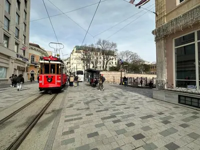 a red trolley train on a street in a city at ŞAHİN PERA SUİT 1 stylish 2Br 3Ac apartment near Istiklal street in Istanbul