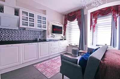 a kitchen with white cabinets and a tv and a couch at Excellent Apartments Galata in Istanbul