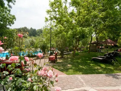 a park with tables and chairs and pink roses at Fener Motel in Sile