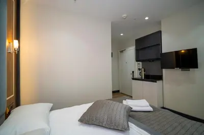 a bedroom with a white bed and a kitchen at Rusel Park Residence in Bahcesehir