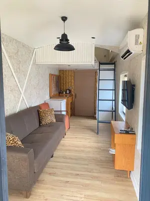 a living room with a couch and a kitchen at King Pansiyon in Karamandere