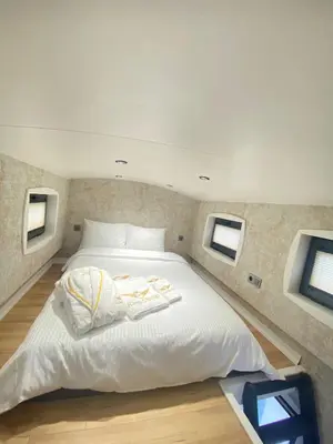 a large white bed in a room with two windows at King Pansiyon in Karamandere