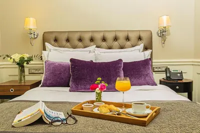 a tray of food and drinks on a bed with purple pillows at Meroddi Bağdatlıyan - 1892 Heritage Rooms by Galata Tower in Istanbul