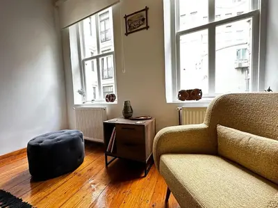 a living room with a couch and a table and two windows at Historical Flat in Galata - Tatar Beyi Street - TRA 2026 Award-Winner in Istanbul