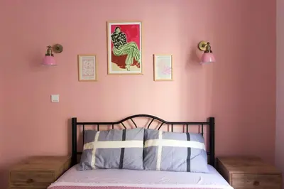 a bedroom with a bed with pink walls and two lights at Soft modern inspiring flat in the center of Moda in Istanbul