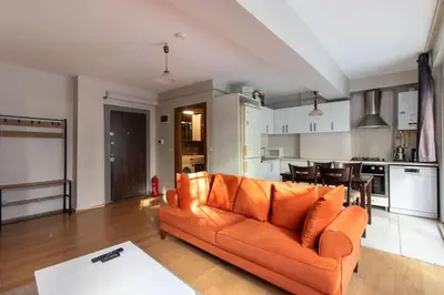 a living room with an orange couch and a kitchen at Cozy Modern 1BR w Patio New Building in Maltepe in Istanbul