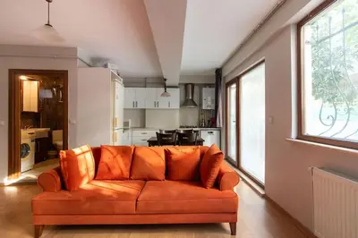 an orange couch in a living room with a kitchen at Cozy Modern 1BR w Patio New Building in Maltepe in Istanbul