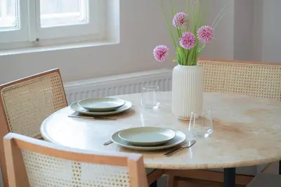 a table with plates and a vase with flowers on it at Designed and Modern 2BR Flat In Center Of Buyukada in Adalar