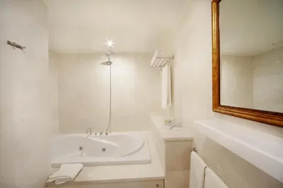 a white bathroom with a tub and a mirror at Grand Hotel de Pera in Istanbul