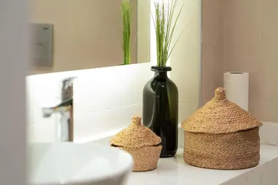 a bathroom counter with a black vase and two baskets at Bright and Cozy 2BR Apt In The Center Of Buyukada in Adalar