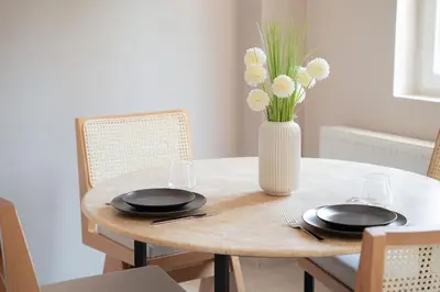a table with two plates and a vase with flowers at Bright and Cozy 2BR Apt In The Center Of Buyukada in Adalar