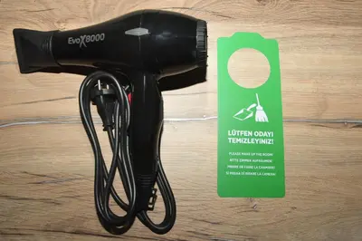 a black hair dryer on a table next to a card at Alessia Old City in Istanbul